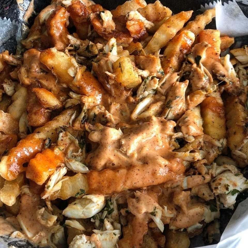 LuLu's Express seafood fries, topped with crab meat and a creamy orange sauce.