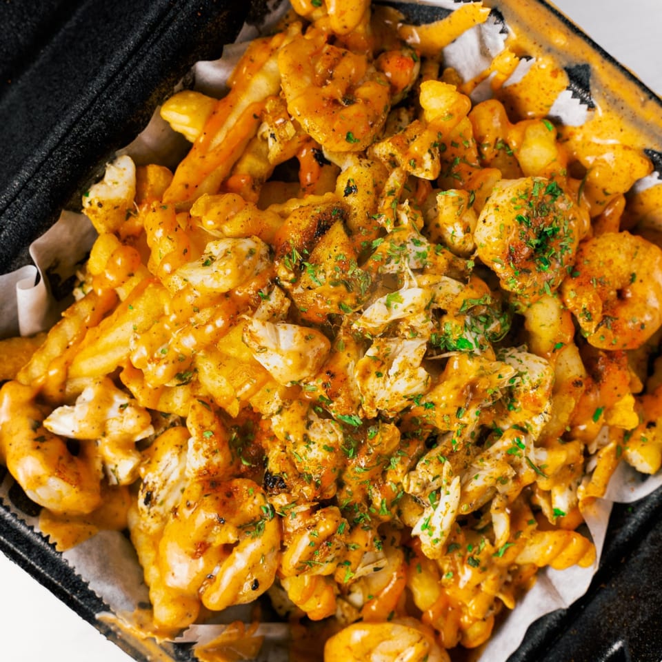 LuLu's Express seafood fries, topped with shrimp, crab meat, cheese sauce, and parsley.